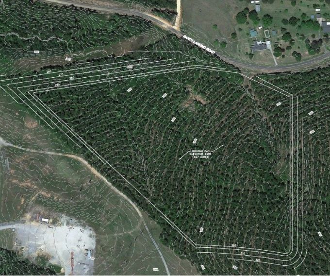 Tree-covered vacant land with elevation markings and location of future building.