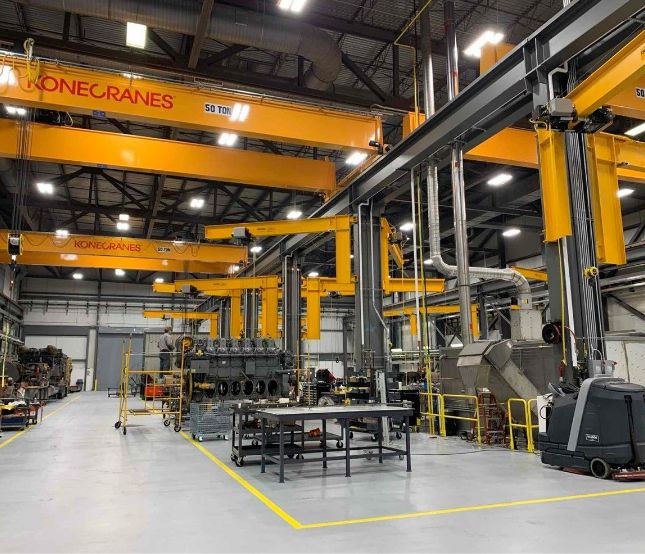 Large yellow cranes inside engine rebuild facility.