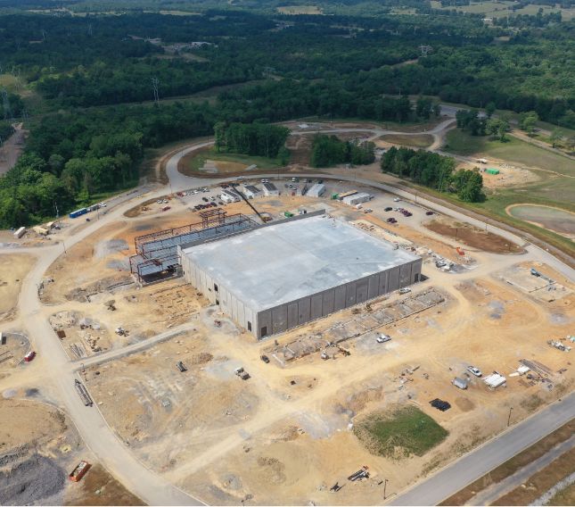 Drone image of full construction site showing building exterior and access roads.