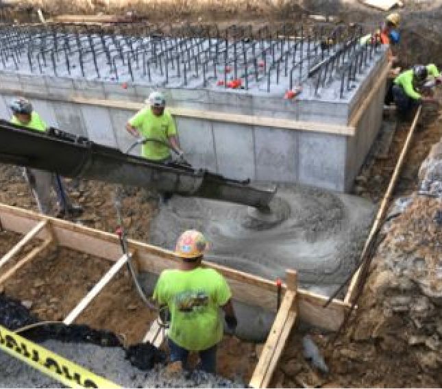 Construction team standing in foundation as concrete is poured